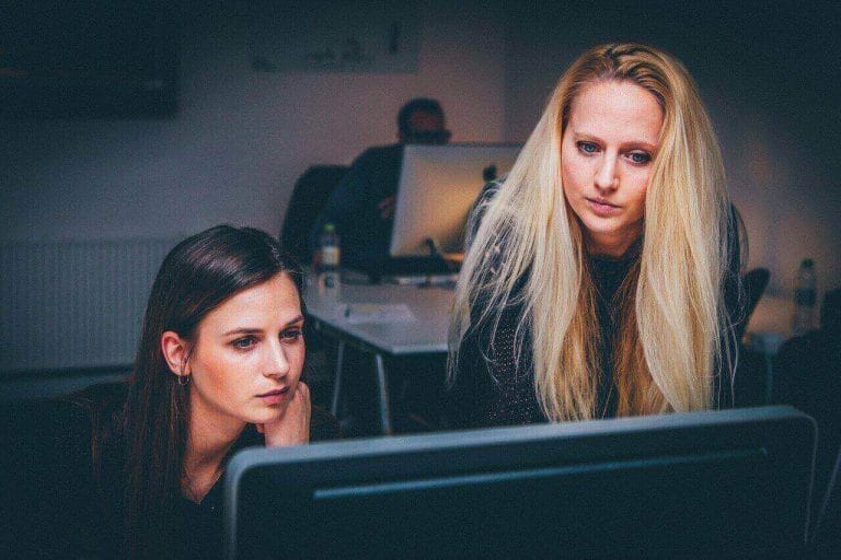 duas mulheres em frente ao computador olhando para tela